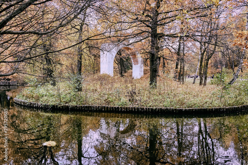 Fototapeta Naklejka Na Ścianę i Meble -  Picturesque autumn landscape, old ruined stone arch on the island with forest and river. Natural vintage background