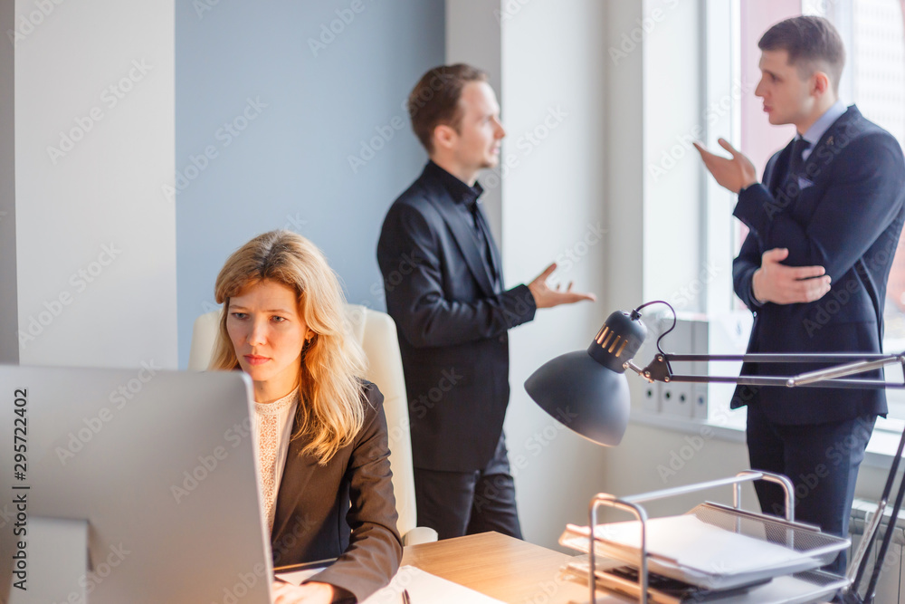 Woman working on pc and men discussing in the background in modern office. Woman working on pc and men discussing in the background in modern office.