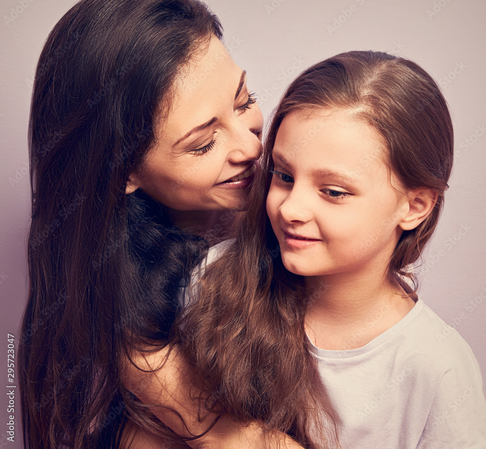 Happy mother and excited joying kid girl hugging with emotional smiling faces on purple background with empty copy space. Happy mother and excited joying kid girl hugging with emotional smiling faces on purple background with empty copy space.