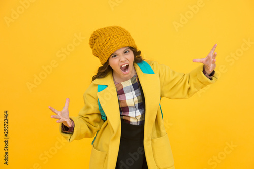 Rrrrr. Little schoolchild roar frightfully. Angry little kid on yellow background. Unhappy little girl back to school. Little child in autumn fashion wear photo