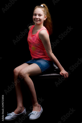 A teenage girl is sitting on a leather chair.