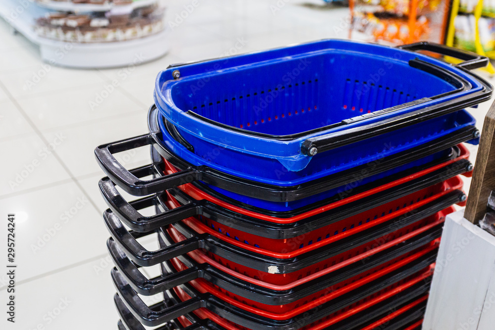 Blue and Red folded supermarket basket on the background of the interior of  the supermarket. Empty baskets for future purchases lie waiting for the  buyer. Stock Photo | Adobe Stock