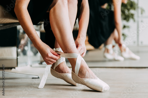 Close up for ballet dancer putting on, tying ballet shoes. Ballerina putting on her pointe shoes