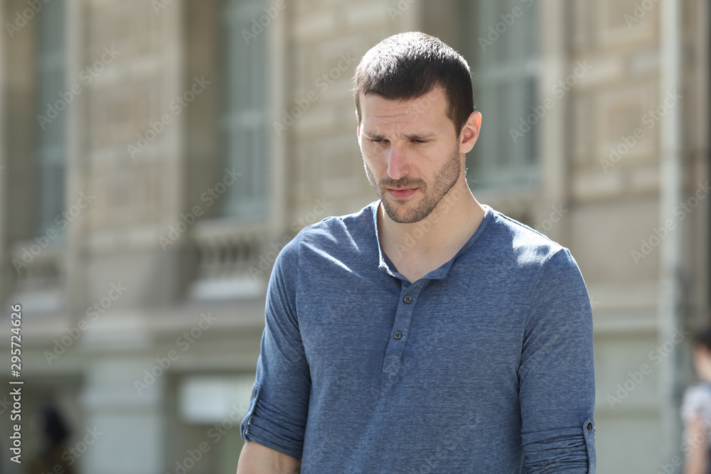 Sad adult man walking looking down in the street Sad adult man walking looking down in the street