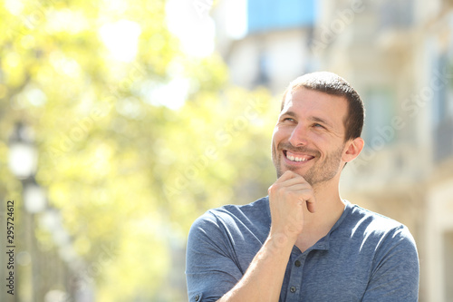 Happy adult man thinking looking at side in the street