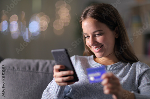 Happy woman buying with phone and credit card at home photo