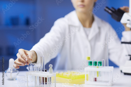 Close up of unrecognizable female scientist holding test tubes while doing research in medical laboratory, copy space
