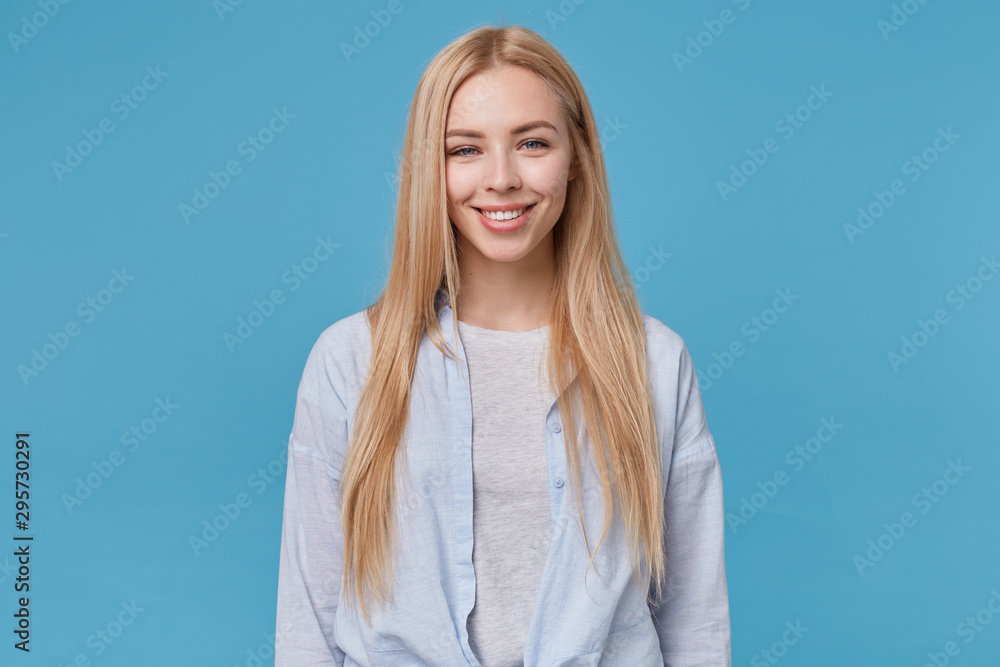 Φωτογραφία Studio photo of lovely young long haired woman wearing blue shirt and grey t-shi