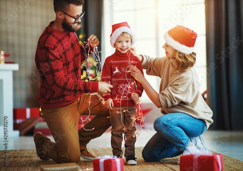 Fotografie happy family decorate Christmas tree, parents play with child son with garlands