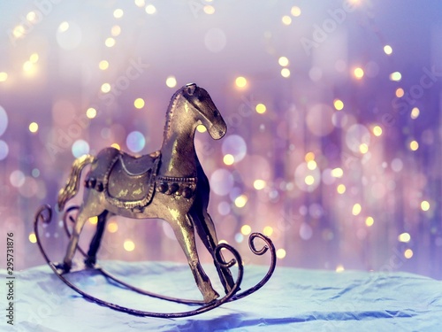 Gilded rocking horse in retro style on a background of bokeh and yellow lights