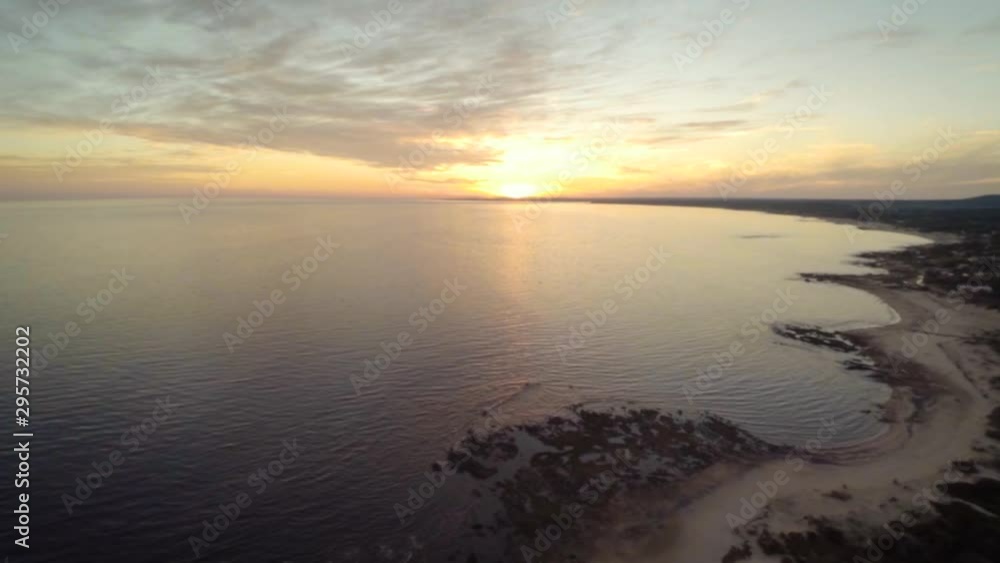 A drone shot at sunset of Playa Hermosa, in Piriapolis, Maldonado, Uruguay. The drone flies up over the calm water rippling to the shoreline in the calm evening. A drone shot at sunset of Playa Hermosa, in Piriapolis, Maldonado, Uruguay. The drone flies up over the calm water rippling to the shoreline in the calm evening.