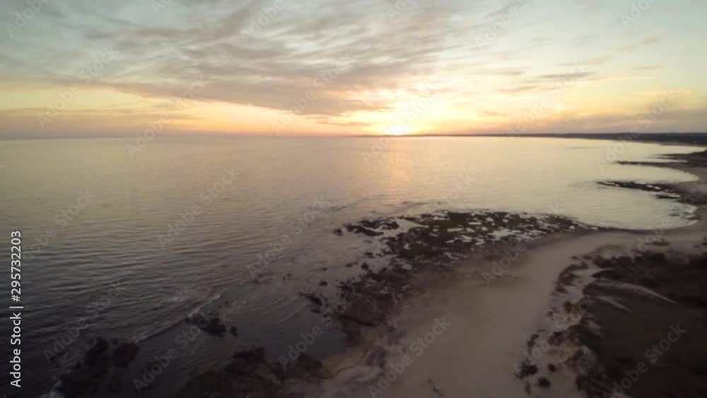 A drone shot at sunset of Playa Hermosa, in Piriapolis, Maldonado, Uruguay. The drone lowers over the calm water rippling to the shoreline in the calm evening. A drone shot at sunset of Playa Hermosa, in Piriapolis, Maldonado, Uruguay. The drone lowers over the calm water rippling to the shoreline in the calm evening.