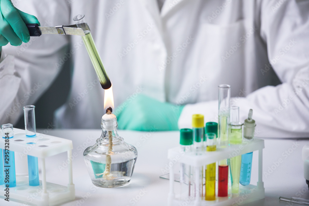Fototapeta premium Close up of unrecognizable scientist holding test tube over gas burner while working on research experiment in laboratory, copy space