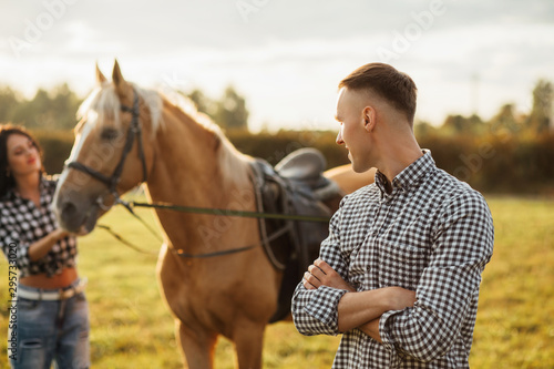 Portrait of happy loving couple spending time with horses on ranch