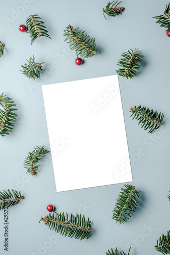 Blank card with fir tree branches red berries and star confetti on blue background