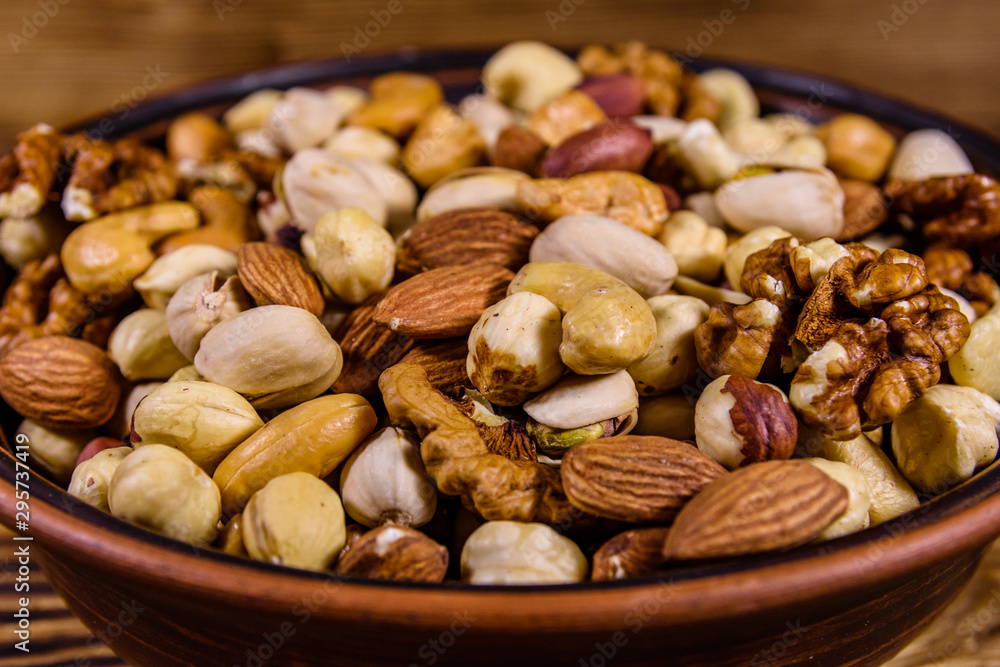 Various nuts (almond, cashew, hazelnut, pistachio, walnut) in ceramic plate on a wooden table. Vegetarian meal. Healthy eating concept Various nuts (almond, cashew, hazelnut, pistachio, walnut) in ceramic plate on a wooden table. Vegetarian meal. Healthy eating concept