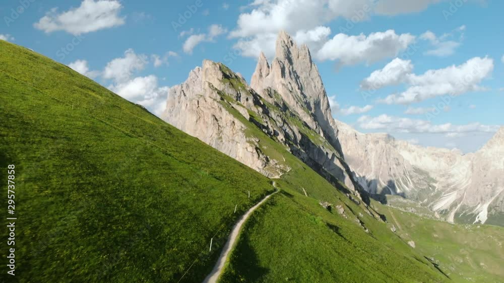 Mountain peaks in the Alps with blooming pastures and hiking trail in summer