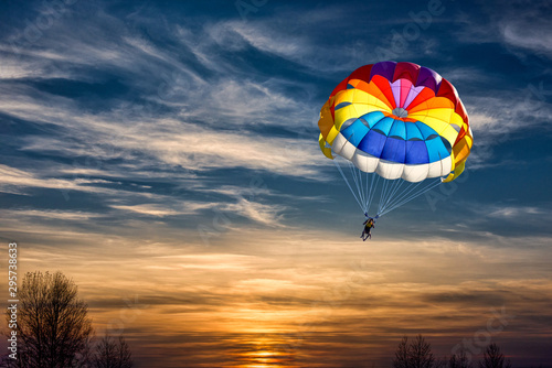 People are gliding with a parachute on the background of sunset. photo
