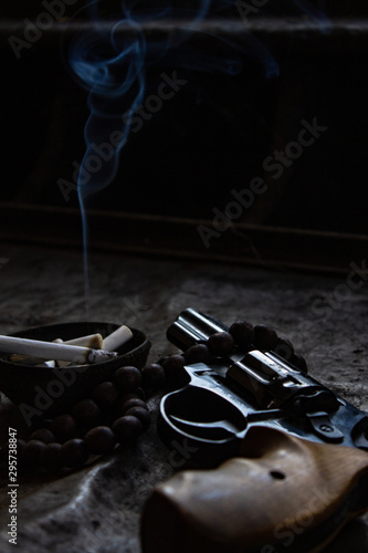 Revolver and rosary. Revolver and rosary with an ashtray.