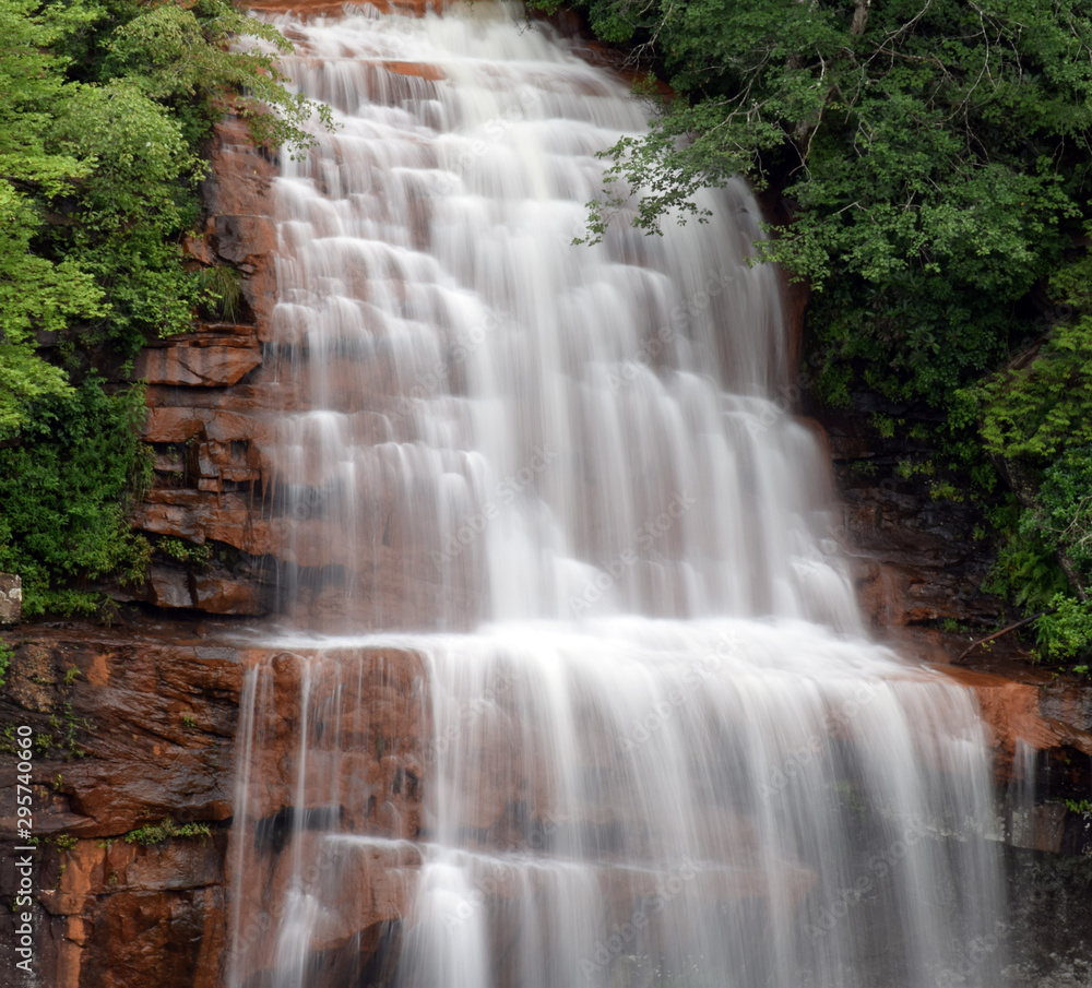Fototapeta premium A waterfall cascades over red rock.