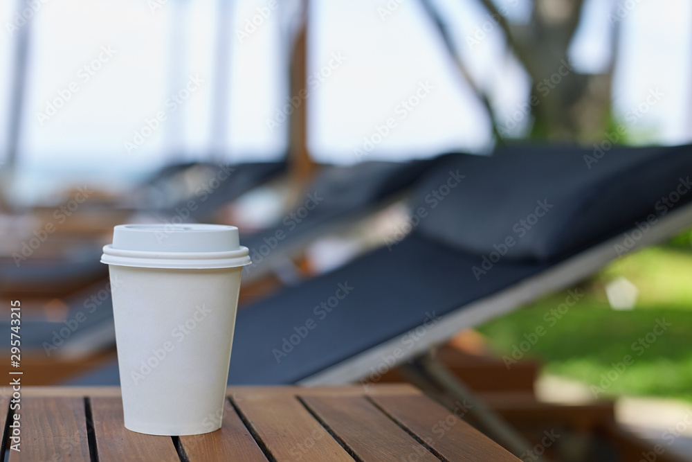 Takeaway cup of coffee on table at beach hotel Takeaway cup of coffee on table at beach hotel