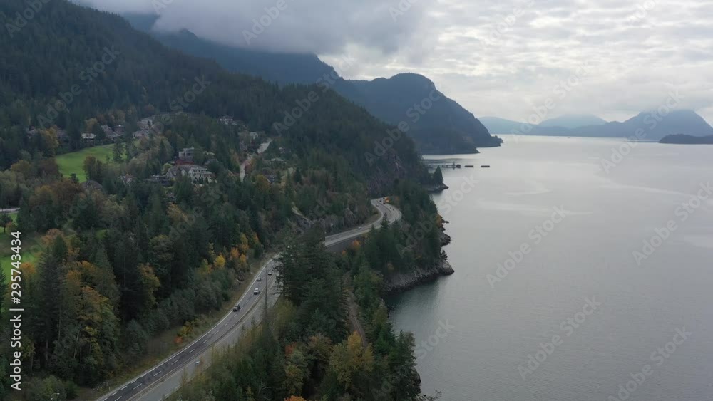Aerial view over inlet, ocean and island with boat and mountains in beautiful British Columbia. Canada. 4K.