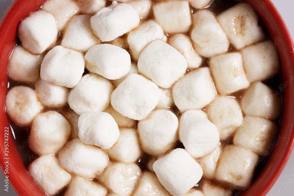 Red ceramic cups of hot cocoa with marshmallows on top of white marble background Red ceramic cups of hot cocoa with marshmallows on top of white marble background