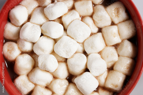 Red ceramic cups of hot cocoa with marshmallows on top of white marble background