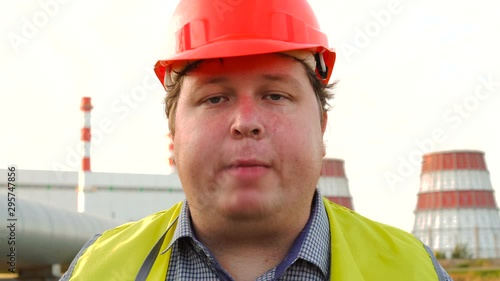 Worker, engineer, or electrician looking directly at the camera reads a tongue twister in front of a power station
