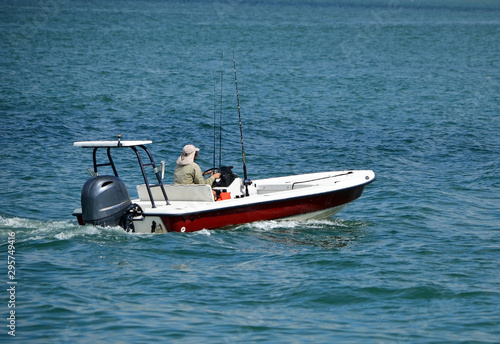 Red and white fishing skiff powered by a single outboard engine