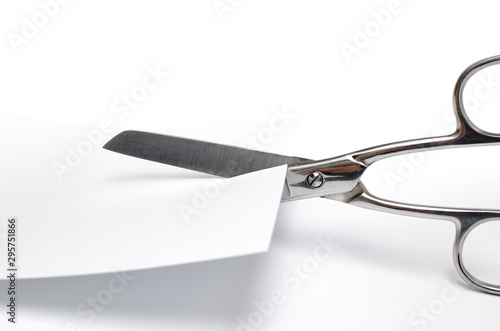 Scissors cut a white sheet of paper on a white background.