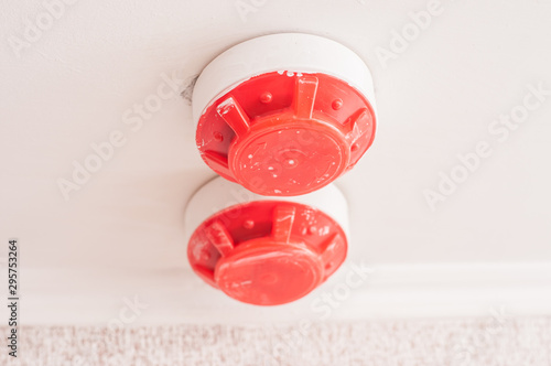 Red color fire detector mounted on the ceiling. Sensor triggered by smoke. photo