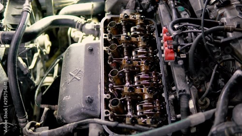 Car mechanic in garage with old car engine piston and valve photo