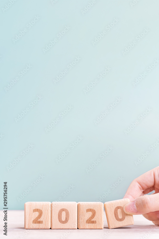 Abstract 2020 & 2019 New year countdown design concept - woman holding wood blocks cubes on wooden table and green background, close up, copy space. Abstract 2020 & 2019 New year countdown design concept - woman holding wood blocks cubes on wooden table and green background, close up, copy space.