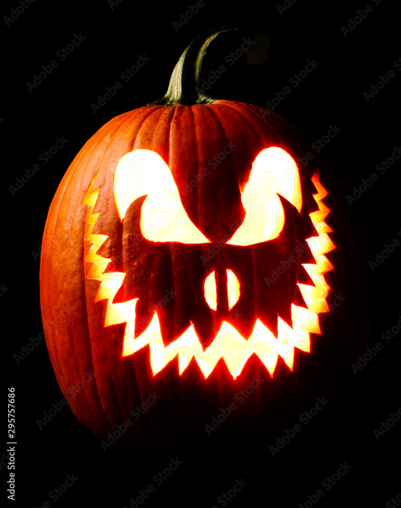 Fototapeta premium Halloween carved Jack o lantern pumpkin glowing eerily in the dark