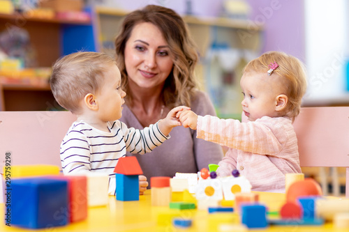 Little caucasian babies playing with Montessori toy in pre-school, creche or kindergarten