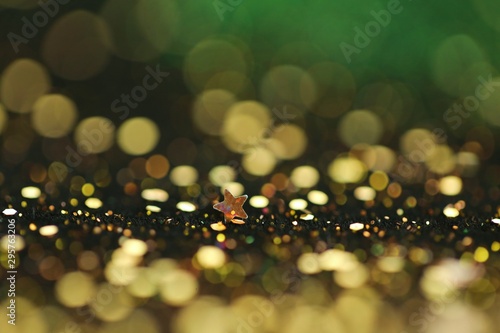 Festive bokeh background.Star and gold glitter with yellow bokeh on a black-green background.Christmas and New Year background.Winter holidays wallpaper.