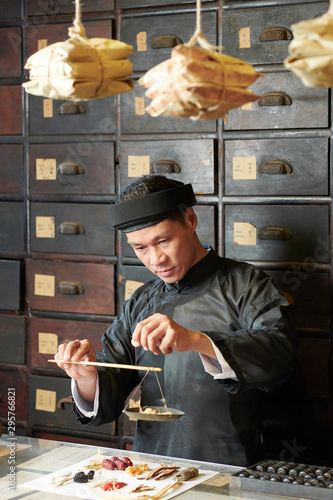 Fotografie Chinese medicine practitioner using scales to measure dry ingredients for the tr