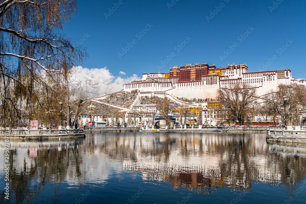 Stunning view and reflection of the famous Potala Palace in the heart of Lhasa in Tibet province in China on a sunny winter day with snow covered moutntains in the background