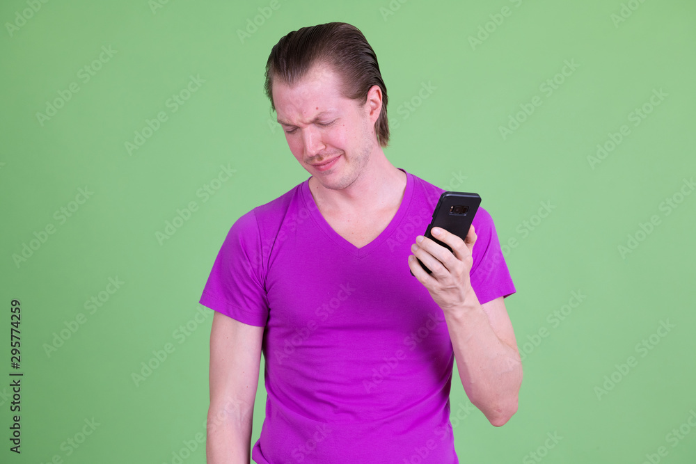 Portrait of stressed young man using phone and looking sad Portrait of stressed young man using phone and looking sad