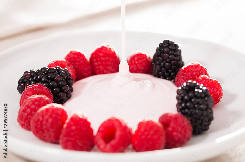fresh raspberries and blackberries laid out on a white plate in circle with yogurt fresh raspberries and blackberries laid out on a white plate in circle with yogurt