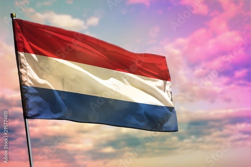 Fluttering Netherlands flag on colorful cloudy sky background. Prosperity concept.