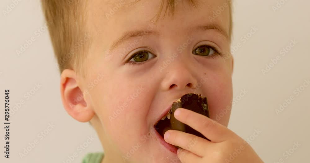 Adorable kid looking up with laugh and eating tasty chocolate Adorable kid looking up with laugh and eating tasty chocolate