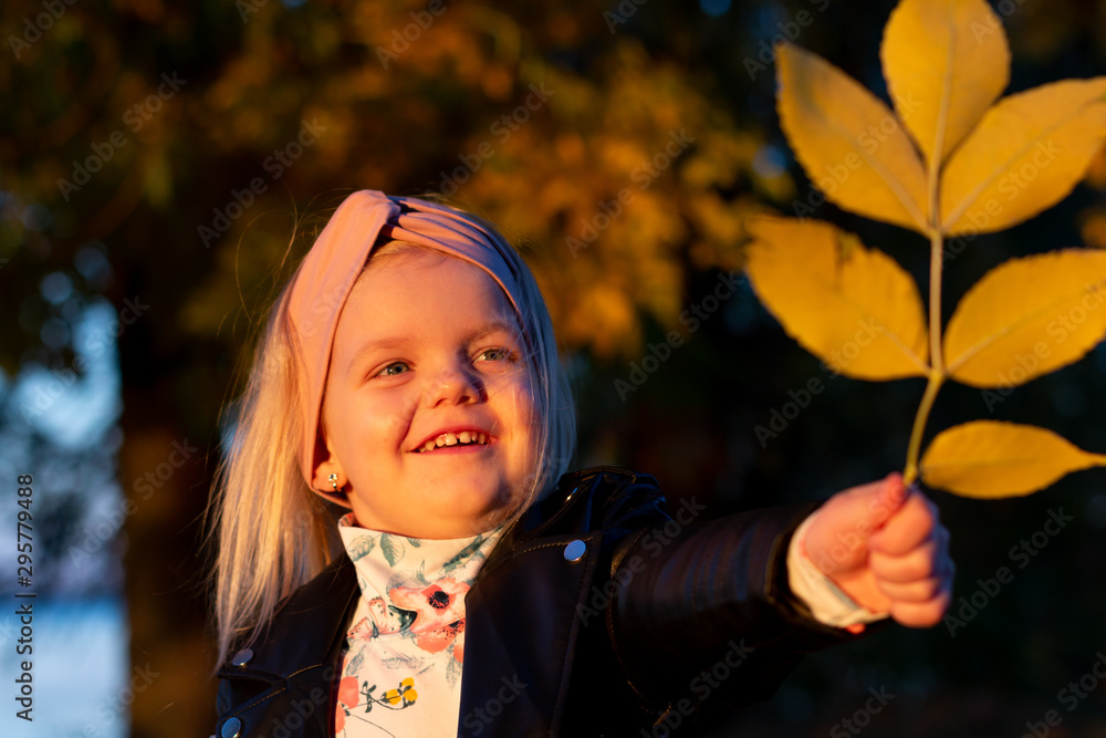 Little girl in a leather jacket, playing in the autumn park. Little girl in a leather jacket, playing in the autumn park.