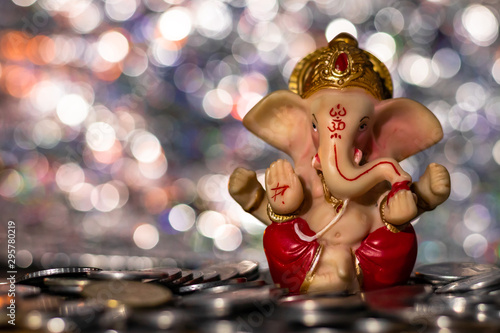 Front shot of a Ganesha statue for Diwali decoration - natural lighting and a pile of coins in the foreground