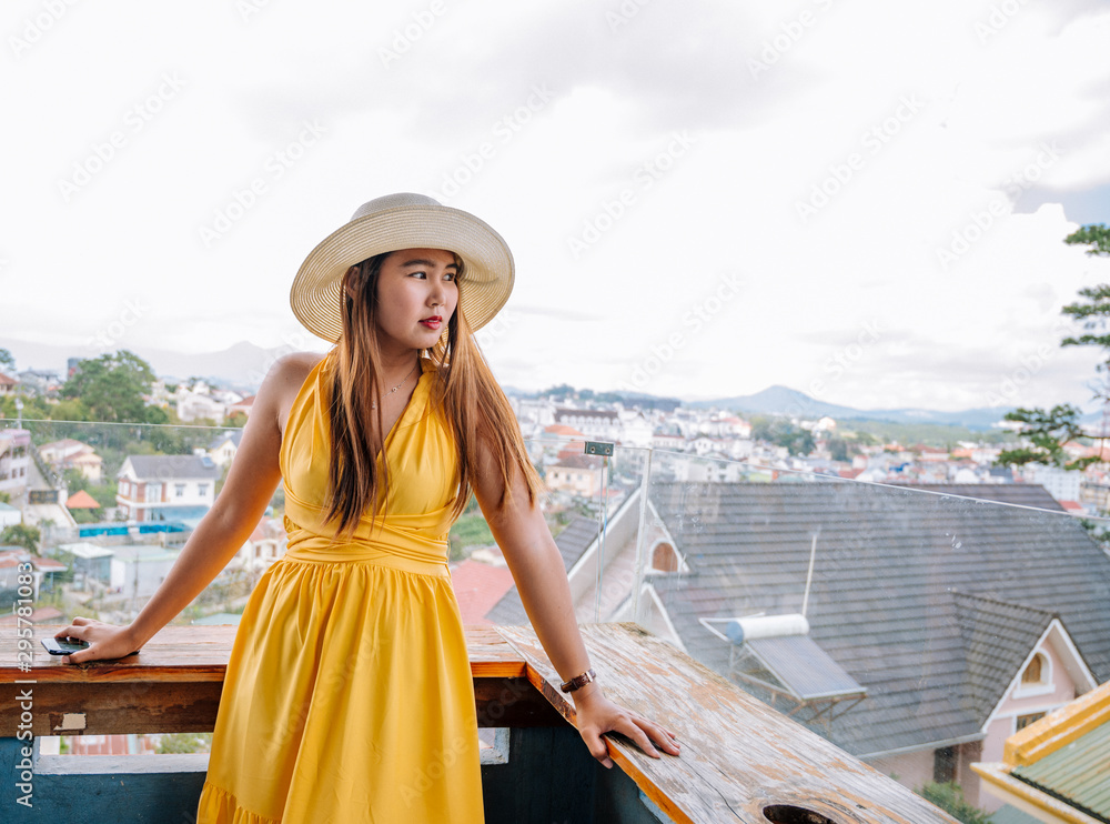 Asian young woman with yellow dress and hat looking the city travel concept in urban background.