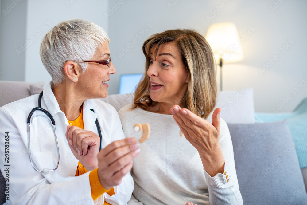 Modern hearing aids.The choice of hearing aid in the doctor's office. Doctor showing hearing aid. Otolaryngologist giving hearing aid to patient. The hearing aid for a senior woman Modern hearing aids.The choice of hearing aid in the doctor's office. Doctor showing hearing aid. Otolaryngologist giving hearing aid to patient. The hearing aid for a senior woman