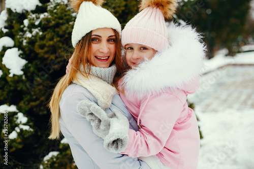 Family have fun in a winter park. Stylish mother in a blue jacket. Little girl in a winter clothes.