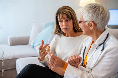 The doctor laryngologist explains senior woman how to wear a hearing aid. Mature female doctor hearing specialist in her office Showing Hearing Aid To female Patient In Clinic
