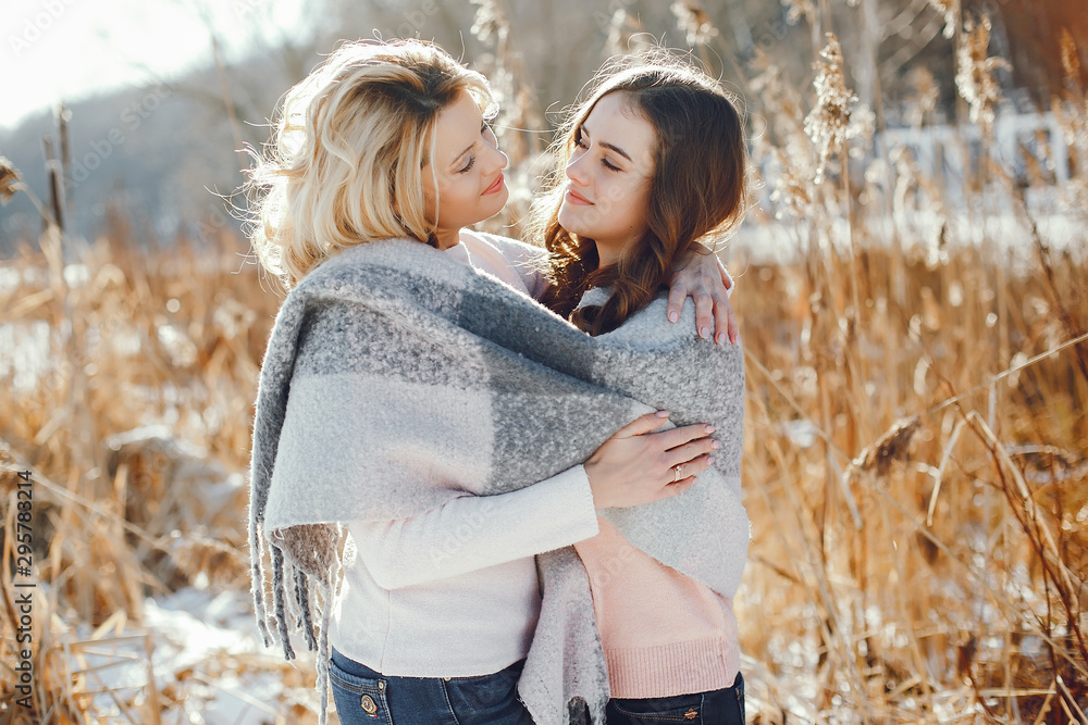 Fototapeta premium young blonde mom with her grown up daughter in the spring park